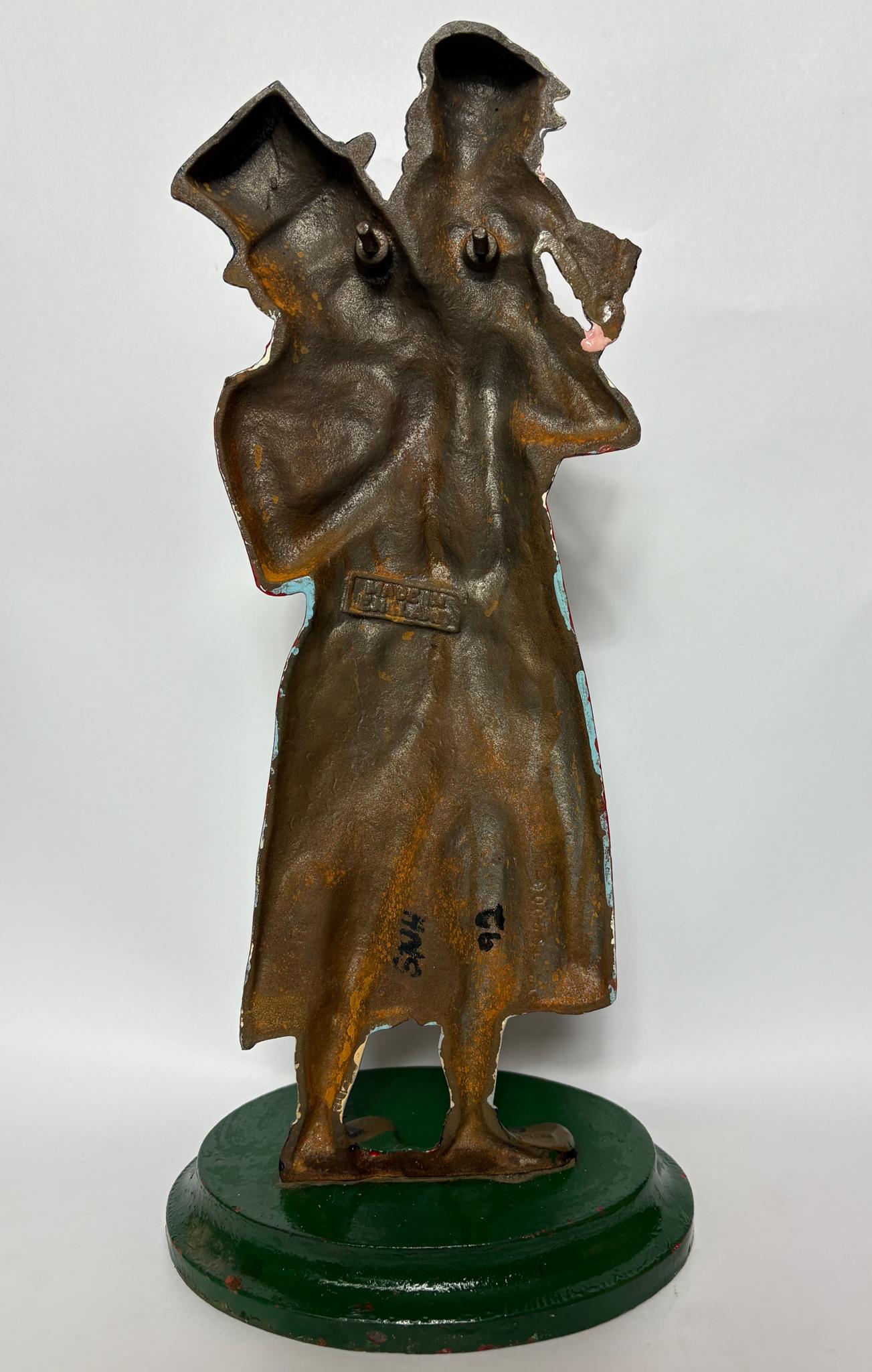 Early 20th‑century cast‑iron doorstop of Bob Cratchit & Tiny Tim from Dickens’ A Christmas Carol.